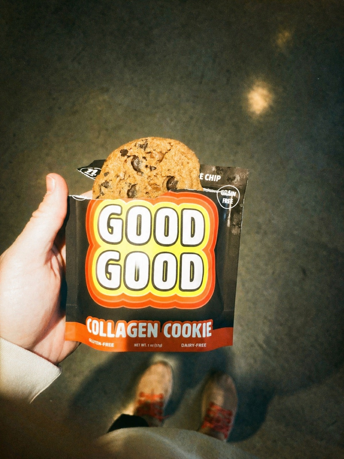 Hand holding a GOOD GOOD Collagen Cookie chocolate chip in its retro orange-and-yellow grain-free, gluten-free, dairy-free package
