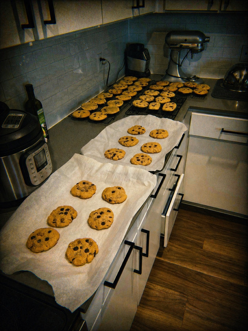 Trays of homemade chocolate chip cookies cooling on parchment in Brad's apartment kitchen